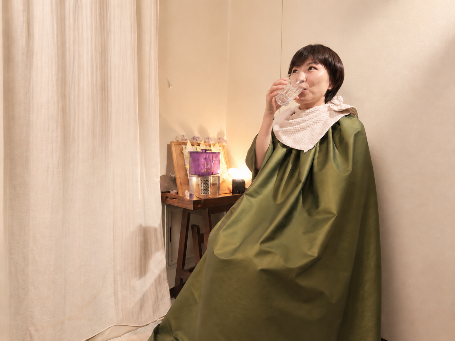 専用マントを着て漢方よもぎ蒸しを受ける女性