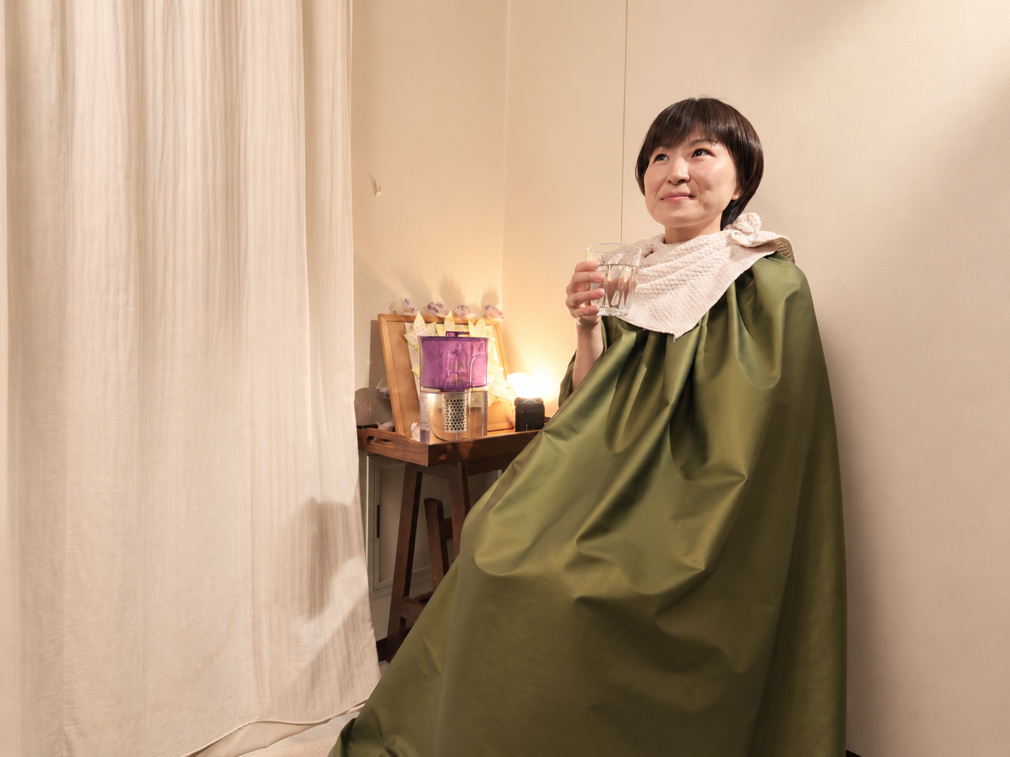 漢方よもぎ蒸しを受けながら水分補給をする女性